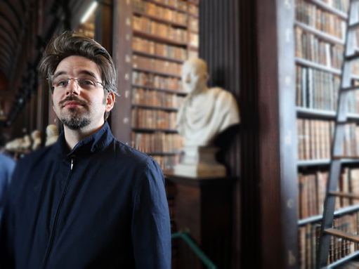 Daniel Pettersson with bookshelves and a marble bust of Cicero in the background, at the Trinity College Library, Dublin.