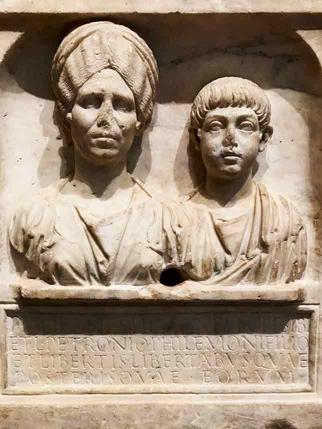 Funerary inscription in stone from early 2nd century with busts of a Roman woman and a young boy.