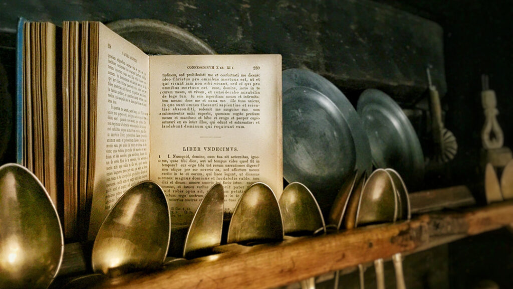 Augustinus' Confessiones open in the middle, standing amongst spoons and old plates in a kitchen.